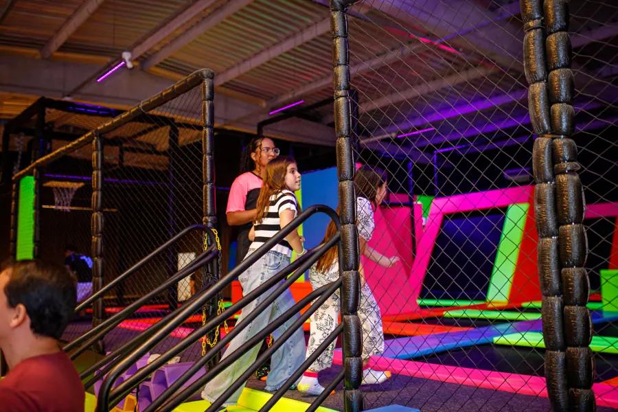 Visitantes na área de trampolins com rede de proteção